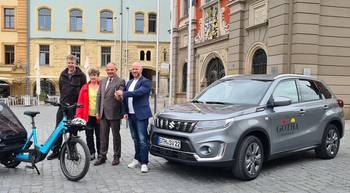 Oberbürgermeister Knut Kreuch und Mitarbeitende der Stadtverwaltung stehen mit einem neuem PKW und einem Lastenrad auf dem Hauptmarkt.