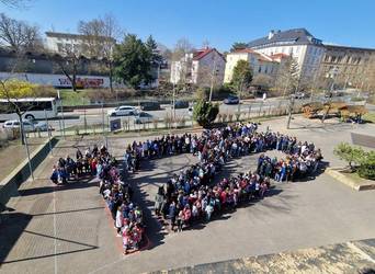 Kinder bilden auf einem Schulhof eine große Ziffer 125