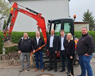 Gruppenbild vor einem Bagger, öffnet größere Ansicht