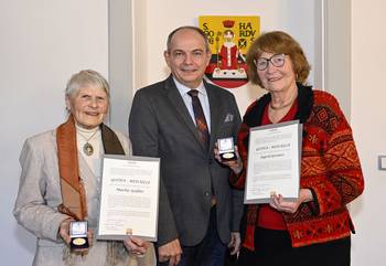Stadtführerinnen Marlis Gießler und Ingrid Greiner stehen mit Oberbügermeister Knut Kreuch vor dem Gothaer Stadtwappen