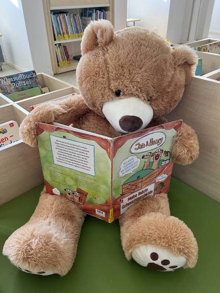 Ein Teddybär mit einem Kinderbuch, öffnet größere Ansicht
