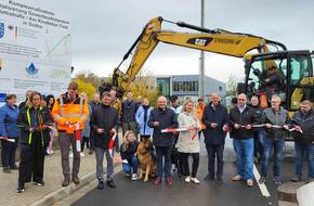 Ein Baustellenband wird durchggeschnitten und eine neu gebaute Straße freigegeben, öffnet größere Ansicht.