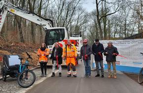 Ein Radweg wird für den Verkehr freigegeben, im Hintergrund steht ein Bagger, öffnet größere Ansicht