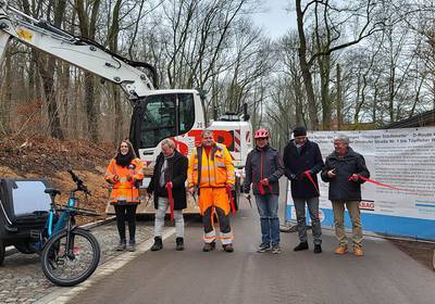 Ein Radweg wird für den Verkehr freigegeben, im Hintergrund steht ein Bagger, öffnet größere Ansicht