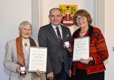 Stadtführerinnen Marlis Gießler und Ingrid Greiner mit der Gotha-Medaille geehrt © Lutz Ebhardt Stadtführerinnen Marlis Gießler und Ingrid Greiner stehen mit Oberbügermeister Knut Kreuch vor dem Gothaer Stadtwappen