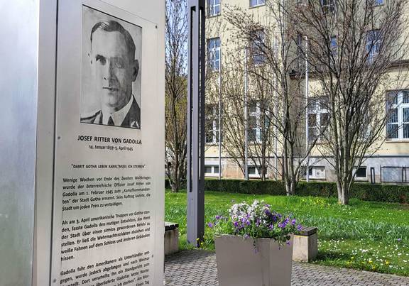 Gadolla-Denkmal vor dem Neuem Rathaus mit einem bunt bepflanzten  Blumenkübel daneben.