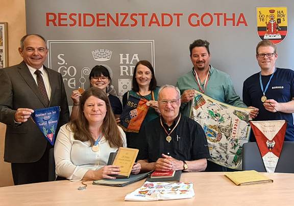 Archiv des Turnvereins Siebleben e.V. an das Stadtarchiv Gotha übergeben Oberbürgermeister Knut Kreuch, Julia Beez (Leiterin Stadtarchiv) un dMitgleider des Siebleber Turnvereins e. V. sitzen an einem Tisch und zeigen Archivmaterialien.