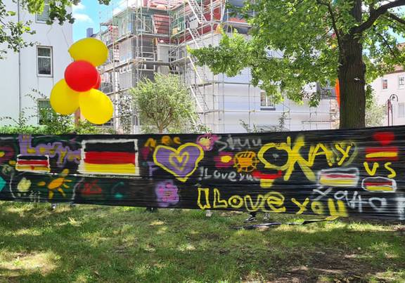 Kooperationsprojekt "Erlebnis-Projekt – Europa ohne Mauern" Viele bunte Graffiti auf einer schwarzen Plane.