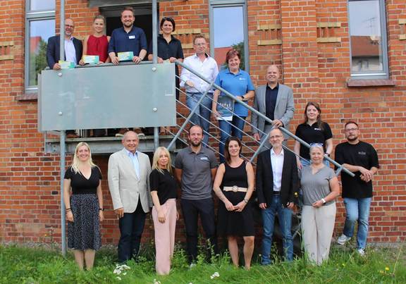 Unternehmerinnen und Unternehmer laden "Zum Tag der offenen Firmen" ein. Gruppenbild von Unternehmerinnen und Unternehmern auf einer Außentreppe, öffnet größere Ansicht.