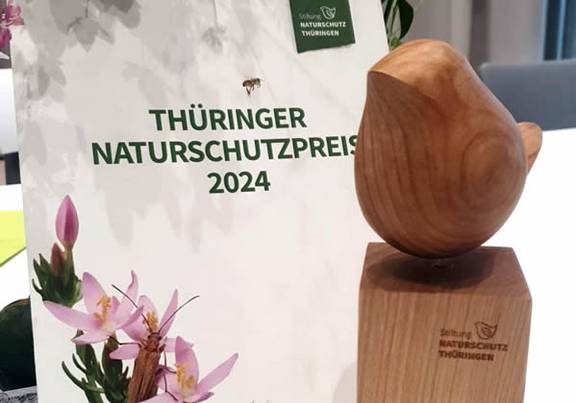 Thüringer Naturschutzpreis 2024 Der Thüringer Naturschutzpreis 2024 steht mit Blumen auf einem Tisch, öffnet größere Ansicht